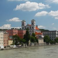 Bunte historische Gebäude säumen das Donauufer in Passau mit barocker Kirche mit Zwillingstürmen und traditioneller Architektur.
