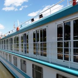 Weißes Flusskreuzfahrtschiff MS Switzerland mit türkisfarbenen Akzenten und großen Fenstern am ruhigen Fluss unter blauem Himmel.