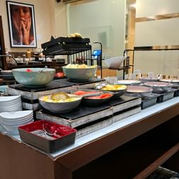 Frühstücksbuffet im Sheraton Essen mit Schüsseln voller Speisen, gestapelten weißen Tellern und Servierschalen auf moderner Theke.