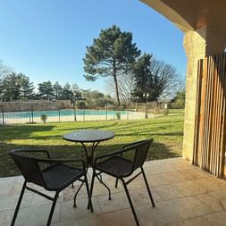 Covered terrace with table and chairs overlooking a lawn and swimming pool at Ceres Boutique Hotel and Spa in Provence.