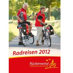 Titelbild des Rückenwind Radreisen Katalogs 2012 mit zwei Radfahrern in roten Westen auf einer von Bäumen gesäumten Straße.