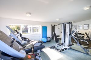 Moderner Fitnessraum im Hotel Seeblick mit Laufbändern, Kraftstation, Gymnastikbällen und natürlichem Licht durch große Fenster.