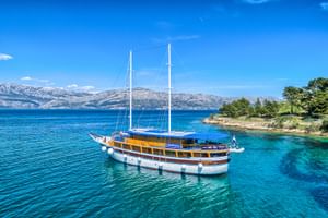San Snova, ein zweimastige Segelschiff mit weißem Rumpf und Holzdeck, vor Anker im türkisfarbenen Adriatischen Meer vor Kroatien.