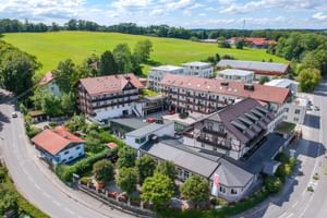 Luftaufnahme des Hotel Seeblick in Bernried mit mehreren Gebäuden mit roten Ziegeldächern, umgeben von grünen Feldern und Bäumen.