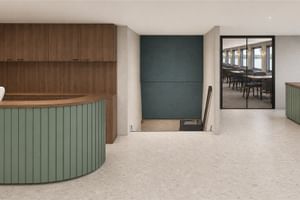 Modern reception area on MS Veloria with curved green reception desk, wood paneling, teal accent wall, and view into dining area.