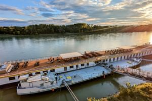 Flusskreuzfahrtschiff MS Prinzessin Katharina am Steg in Bratislava bei Sonnenuntergang. Das weiße Schiff mit Holzdeck liegt an der Donau.