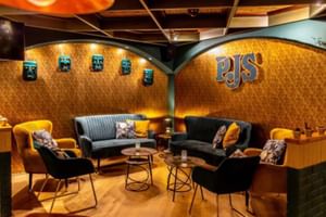 Moderne Hotellobby im Mercure Riesa mit schwarzen Samtsofas, gelben Stühlen, goldenen strukturierten Wänden und PJS-Logo. Blaue Dekoelemente an Wänden.