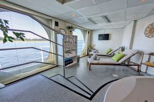 Heller Wellnessbereich auf dem Schiff SE Manon mit Liegen, Badewanne, Sauna und großen Fenstern mit Flussblick.