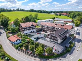 Luftaufnahme des Hotel Seeblick in Bernried mit mehreren Gebäuden mit roten Ziegeldächern, umgeben von grünen Feldern und Bäumen.