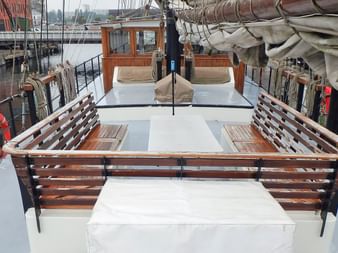 Blick auf das Vorderdeck des Segelschiffs Simmer fan Fryslan mit Holzbänken, weißem Deck, gefalteten Segeln und orangefarbenen Rettungswesten.