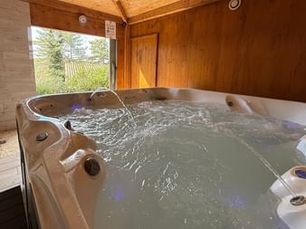 Indoor whirlpool with flowing water in a wooden cabin at Ceres Boutique Hotel and Spa, Provence, with a window overlooking green trees.