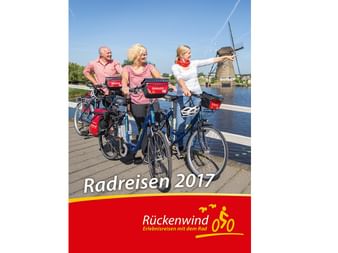 Cover des Rückenwind Radreisen Katalogs 2017 mit drei Radfahrern auf einer Brücke und einer traditionellen Windmühle im Hintergrund.