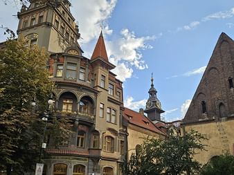 Prächtige historische Gebäude mit Türmen und Turmspitzen in Prag mit farbenfrohen Fassaden und architektonischen Details vor blauem Himmel.