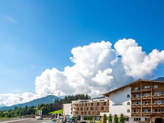Moderner Hotelkomplex in Tirol mit traditioneller Alpenarchitektur, mit Holzbalkonen und weißen Fassaden vor Berglandschaft.