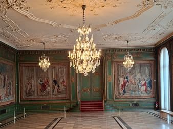 Prunkvoller Saal in der Villa Hügel mit Kristalllüstern, verzierter Stuckdecke, grünen Wänden mit Wandteppichen und poliertem Boden.