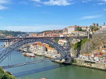 Panoramablick auf Portos ikonische Ponte Luis I Brücke über den Douro mit bunten historischen Gebäuden an beiden Ufern.
