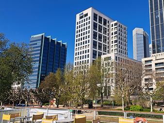 Außenbereich der MS Casanova mit gelben Stühlen und Tischen, mit Blick auf eine moderne Skyline mit Hochhäusern unter blauem Himmel.