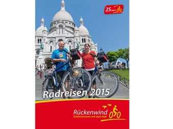 Titelbild des Rückenwind Radreisen Katalogs 2015 mit Radfahrern vor der Basilika Sacré-Cœur in Paris an einem sonnigen Tag.