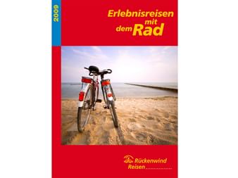 Titelbild des Rückenwind Radreisen Katalogs 2009 mit zwei Fahrrädern am Sandstrand mit ruhigem Wasser im Hintergrund.