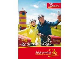 Cover des Rückenwind Radreisen Katalogs 2025 mit zwei Radfahrern mit Helmen vor einem gelb-roten Leuchtturm unter blauem Himmel.