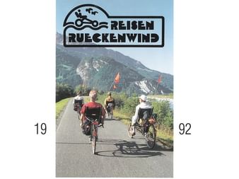 Titelbild des Rückenwind Radreisen Katalogs 1992 mit Radfahrern mit Anhängern auf einer Straße vor Bergkulisse und Firmenlogo oben.