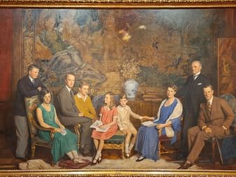Formelles gemaltes Porträt der Familie Krupp in einem prunkvollen Raum der Villa Hügel. Neun Personen in Kleidung der 1920er Jahre vor Wandteppich.