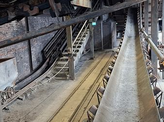 Industrielle Förderbänder und Metallkonstruktionen im historischen Zeche Zollverein Bergwerk in Essen mit Ziegelwänden und Stahlgerüst.
