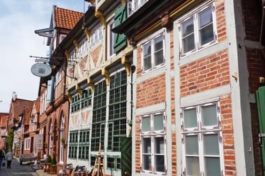 Reihe bunter historischer Fachwerkhäuser in der Lauenburger Altstadt mit roten Backsteinfassaden, weißen Fensterrahmen und grünen Läden.