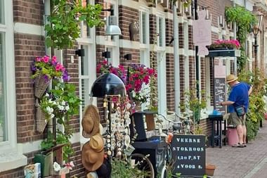 Backsteinladen in Veere mit weißen Fenstern, bunten Blumenkörben, Vintage-Artikeln und einer Kreidetafel auf einer Kopfsteinpflasterstraße.